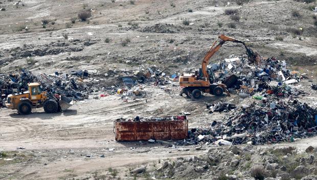 Una grua mueve una montaña de residuos en el exterior del Parque Tecnológico de Valdemingómez