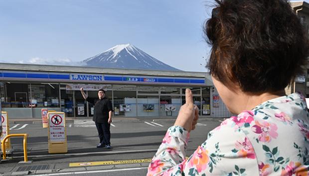 Una persona toma fotografías del Monte Fuji desde el otro lado de la calle