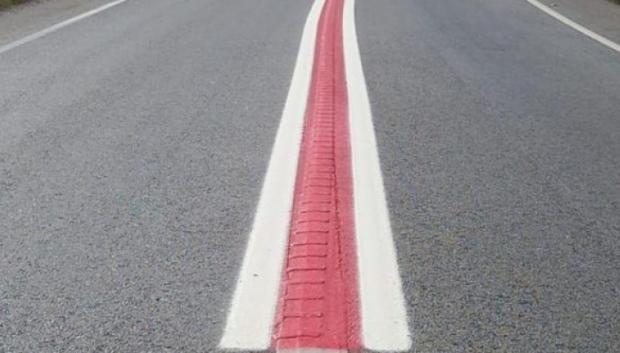 Una línea roja entre dos blancas que delimitan los carriles