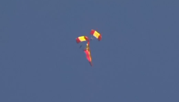Captura del salto de un miembro de la Patrulla Acrobática con la bandera de España en Gijón