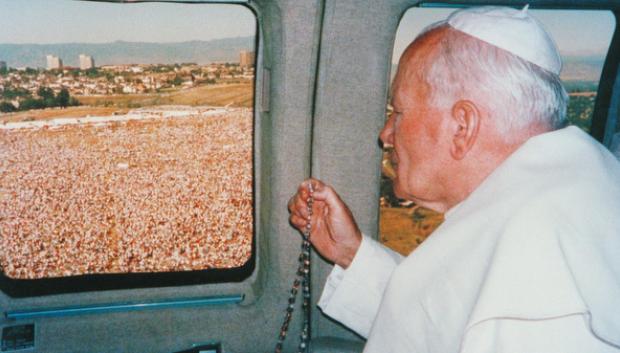 Juan Pablo II, desde el helicóptero y sosteniendo un rosario, contempla la multitud congregada en el Colorado's Cherry Creek State Park de Denver