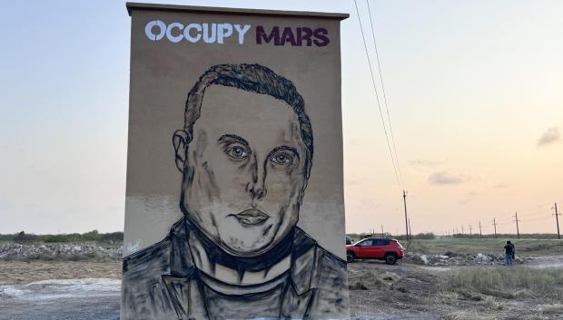 Las casitas con el césped recién cortado no difieren mucho de las de cualquier pueblo texano, pero los grandes murales con la cara de Elon Musk (como el de la imagen), nombres de calles como 'Rocket Road' y la discreción de sus habitantes los delata: está usted entrando en Starbase, "la última parada antes de llegar a Marte".