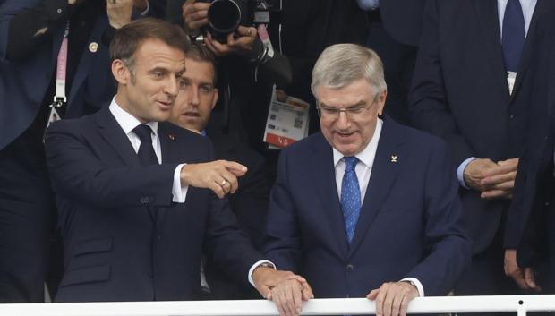 El presidente de Francia, Emmanuel Macron (i), conversa con el presidente del COI, Thomas Bach (d), a su llegada a la tribuna de autoridades en la Plaza del Trocadero