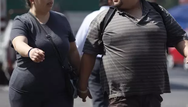 Dos personas con sobrepeso caminan por la calle