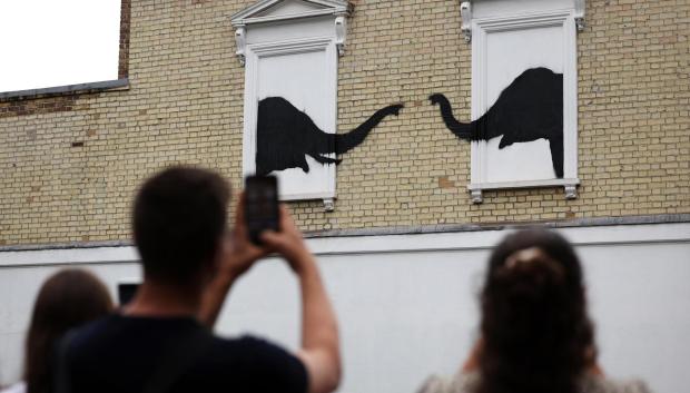 Varias personas fotografían la obra de Banksy