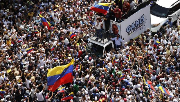 La líder de la oposición venezolana María Corina Machado (c) agita la bandera de Venezuela frente a seguidores este sábado, en Caracas