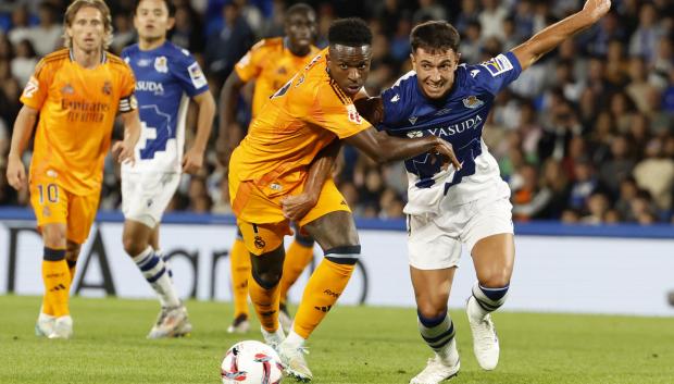 El centrocampista de la Real Sociedad Martín Zubimendi (d) disputa un balón con el delantero del Real Madrid Vinicius