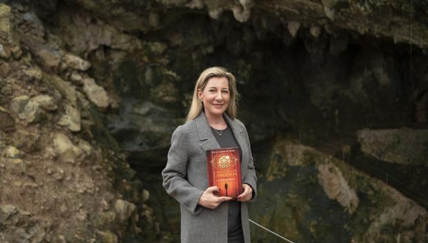 La autora Eva García Sáenz de Urturi en la Cueva Monte Castillo con un ejemplar del libro