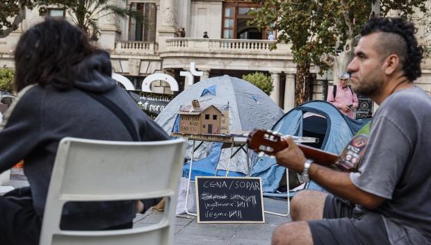 Un hombre toca la guitarra durante la acampada de vivienda en la Plaza del Ayuntamiento de Valencia