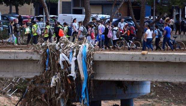 Los voluntarios cruzan un puente cuando llegan a Paiporta para ayudar con la limpieza de la localidad valenciana.