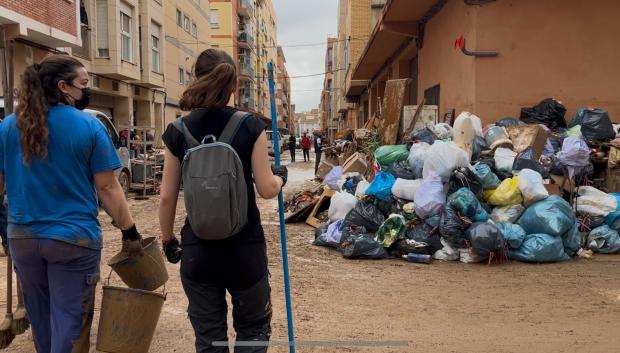 Dos chicas voluntarias pasan al lado de una montaña de basura