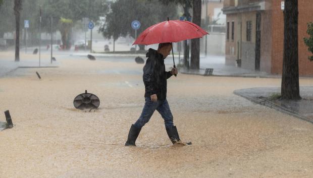 Un hombre caminando por una calle en la barriada de Campanillas en Málaga, en la que el paso de la dana ha obligado a nuevos desalojos preventivos en el río Campanillas ante su posible desbordamiento.  la mayor parte de la provincia malagueña se encuentra en aviso rojo por fuertes lluvias.