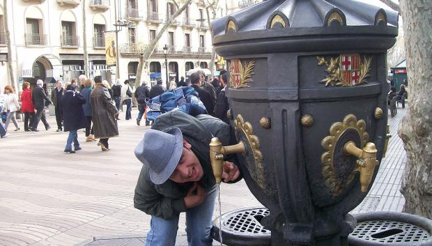 Un hombre bebiendo en la fuente de Canaletas, en Barcelona