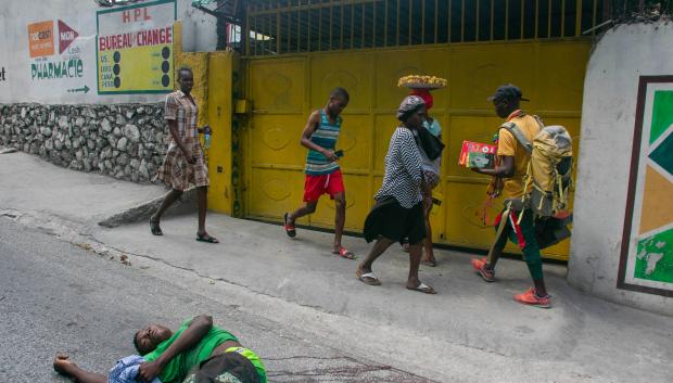 Transeúntes pasan de largo frente al cuerpo sin vida un hombre asesinado, Puerto Príncipe
People walk past the body of a man shot dead by unidentified armed men on the night of March 27 in Port-au-Prince on March 28, 2024.. The situation in chaos-wracked Haiti is "cataclysmic", with more than 1,500 people killed by gang violence so far this year and more weapons pouring into the country, the UN said on March 28,2024. In a fresh report, the United Nations rights office detailed how "corruption, impunity and poor governance, compounded by increasing levels of gang violence (had) eroded the rule of law and brought state institutions... close to collapse". (Photo by Clarens SIFFROY / AFP) / AFP PICTURES OF THE YEAR 2024