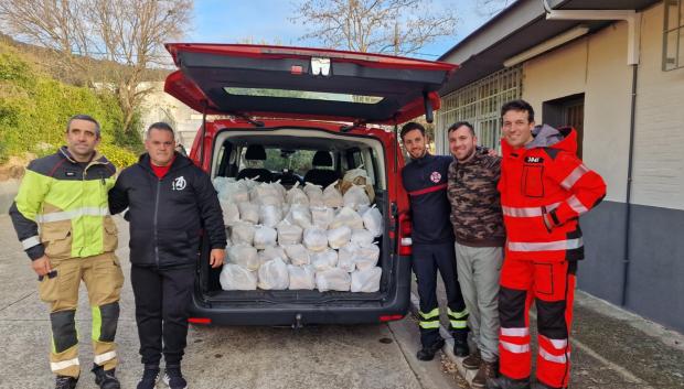 Un grupo de bomberos ayuda a repartir los alimentos