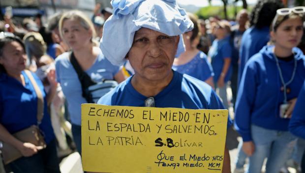 Un hombre sostiene un cartel con una cita del libertador Simón Bolívar que dice 'Pongámonos el miedo en la espalda y salvemos la patria', durante una protesta convocada por la oposición en vísperas de la toma de posesión presidencial en Caracas