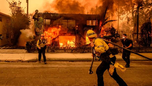 Los bomberos mientras un edificio de apartamentos arde durante el incendio de Eaton en el área de Altadena del condado de Los Ángeles, California