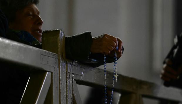 Una persona sostiene un rosario durante las oraciones por la salud del Papa Francisco en la plaza de San Pedro