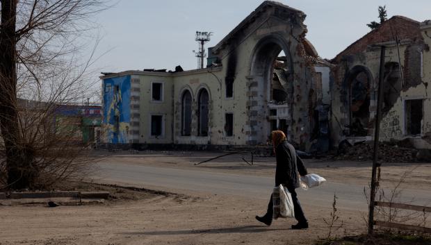 Una mujer con bolsas camina cerca de un edificio dañado en Kostyantynivka, región de Donetsk