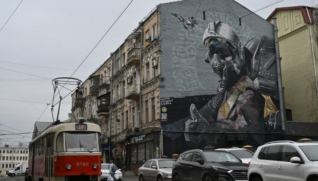 Un tranvía circula por una calle junto a un mural militar titulado "Fantasma de Kiev" en el barrio de Podil, Kiev