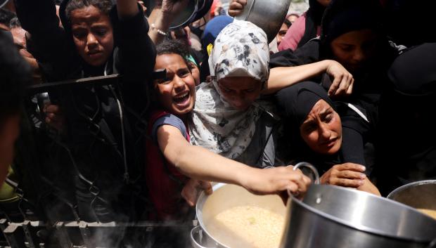 Palestinos luchan por conseguir sus raciones de comida fuera de un abarrotado centro de distribución en Beit Lahia, en el norte de la Franja