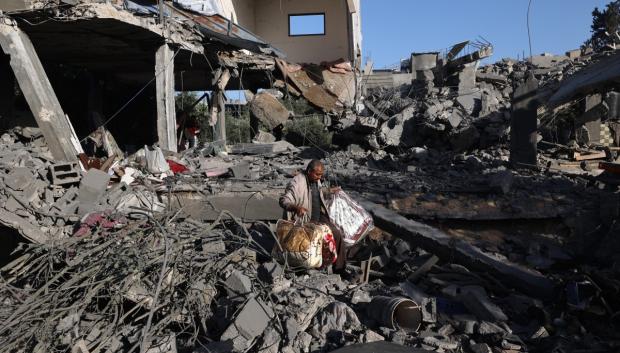 A Palestinian man carries items he salvaged from a house targeted in an Israeli strike at the Nuseirat camp for refugees in the central Gaza Strip on May 24, 2025. (Photo by Eyad BABA / AFP)