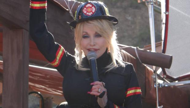 Dolly Parton vestida de bombero en Dollywood, presentando nuevas atracciones.
