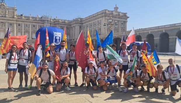 Participantes en la carrera popular con banderas regionales y el guion del Rey