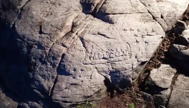 Representación detallada de una barca con 16 figuras y catorce "X" talladas a su lado