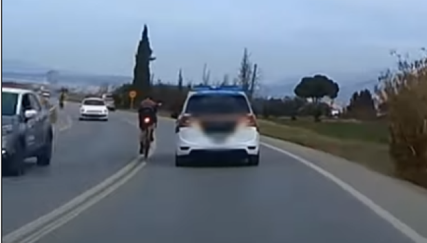 En paralelo, y pisando la línea continua, el ciclista le quita las pegatinas al coche patrulla