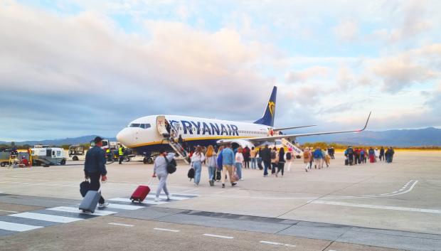Pasajeros con sus maletas camino de un avión de Ryanair en el aeropuerto de Gerona.