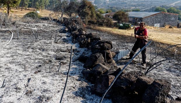 Un hombre trabaja en un muro de su explotación ganadera afectada por el incendio en Las Navas del Marqués (Ávila)