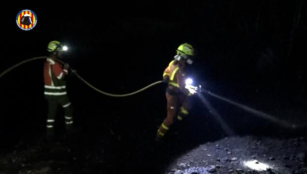 Imagen tomada en la noche de este miércoles de bomberos tratando de extinguir el incendio declarado en Teresa de Cofrentes, Valencia
