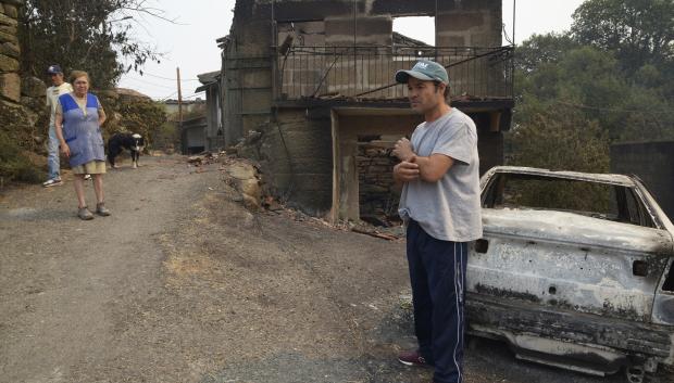Samuel, vecino de A Caridade (Cualedro) delante de su casa destruída por el fuego, igual que propiedades de sus vecinos Dosinda y José Antonio
