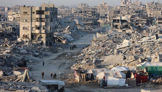 Palestinos caminan junto a los escombros de los edificios destruidos en el barrio Sheikh Radwan de la ciudad de Gaza