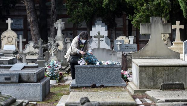 Una mujer lleva flores a un ser querido, en el Cementerio de la Almudena, a 1 de noviembre de 2024