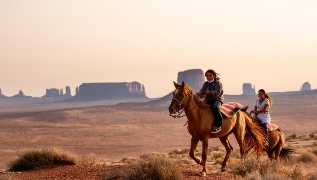 Jóvenes navajo montando a caballo por Monument Valley