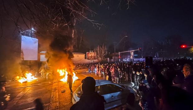 Iraníes se congregan mientras bloquean una calle durante una protesta en Teherán, Irán