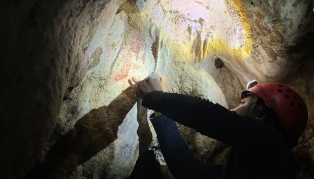 Adhi Agus Oktaviana, investigador especialista en arte rupestre de la agencia nacional de investigación e innovación de Indonesia (BRIN por sus siglas en inglés) trabajando en la cueva de la isla de Célebes (Sulawesi, en el idioma local), en Indonesia, donde se ha encontrado la historia más antigua contada en imágenes conocida hasta ahora