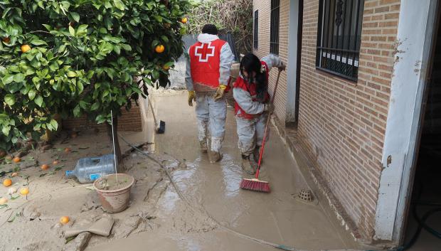 Voluntarios de Cruz Roja retirando barro del exterior de una casa