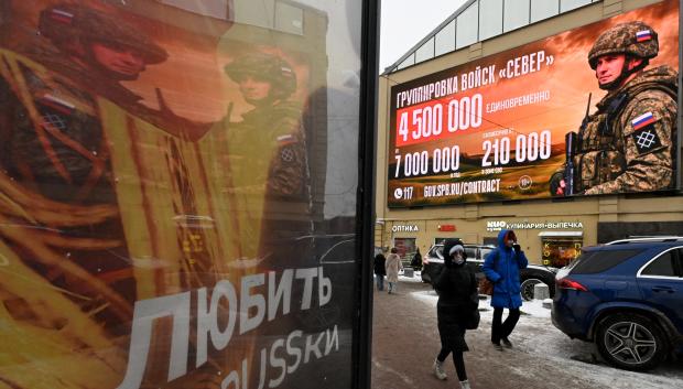 Personas pasan frente a una pantalla digital que muestra un anuncio que promociona el servicio militar por contrato en San Petersburgo