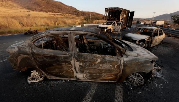 A view of burned cars and trucks, allegedly set on fire by organised crime groups in response to an operation to arrest a high-priority security target, on a highway near Acatlan de Juarez, Jalisco state, Mexico on February 22, 2026. The Mexican army announced that it had killed powerful drug lord Nemesio "El Mencho" Oseguera in an operation that sparked a wave of violence in various parts of the country on February 22, 2026. Gunmen retaliating for the raid blocked more than 20 roads in western Jalisco state, which esi:includes Tapalpa, with burning cars and trucks. The violence spread to other states as well. (Photo by Ulises Ruiz / AFP)
