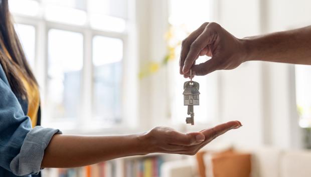 Close-up on a real estate agent giving the keys of her new house to a woman – home ownership concepts