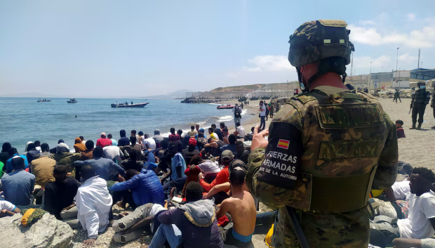 Un soldado del Ejército de Tierra observa a un grupo de inmigrantes que han logrado cruzar uno de los espigones fronterizos de Ceuta