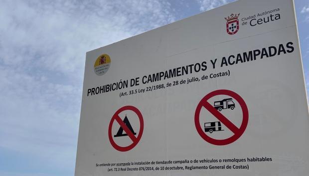 Cartel donde se anuncia la prohibición de acampar en la playa de El Trampolín, donde se amontonan cientos de inmigrantes