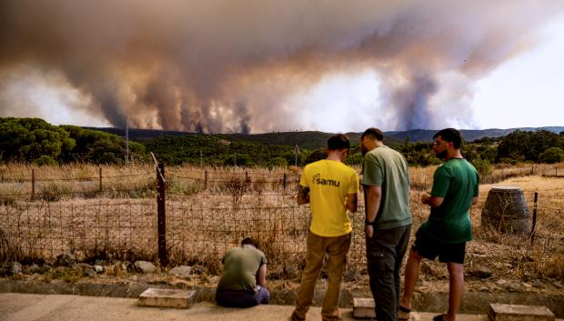 Vecinos de El Madroño, en Sevilla, observan este domingoo el fuego del incendio de Niebla (Huelva),