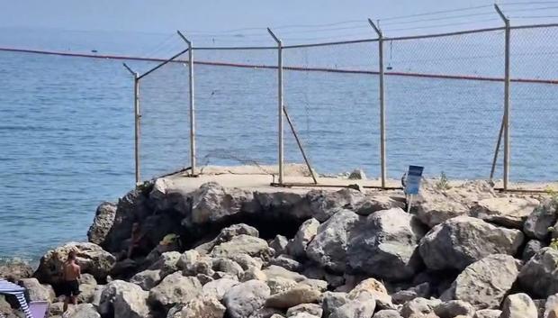 La valla que separa la playa del inicio de la frontera en el lado español se mantiene rota