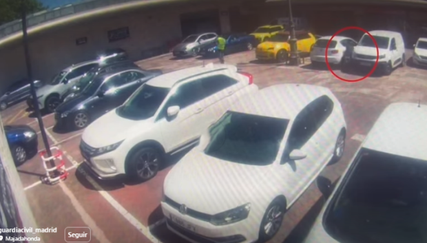 El delincuente, entre ambos coches, en el momento del robo