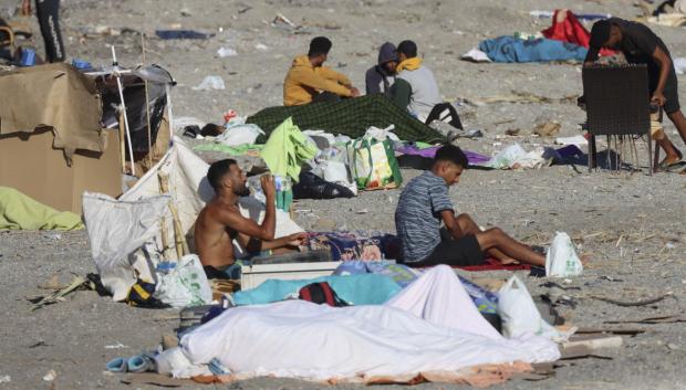 Varios inmigrantes permanecen acampados este sábado en la playa El Trampolín de Ceuta.