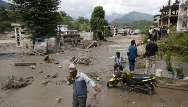 Campesinos avanzan entre el lodo en Trishuli, en el distrito nepalí de Nuwakot, tras una riada repentina.